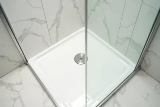 Receveur de douche extra plat encastré dans le sol d'une petite salle de bain avec carrelage blanc et paroi en verre