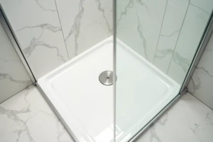 Receveur de douche extra plat encastré dans le sol d'une petite salle de bain avec carrelage blanc et paroi en verre